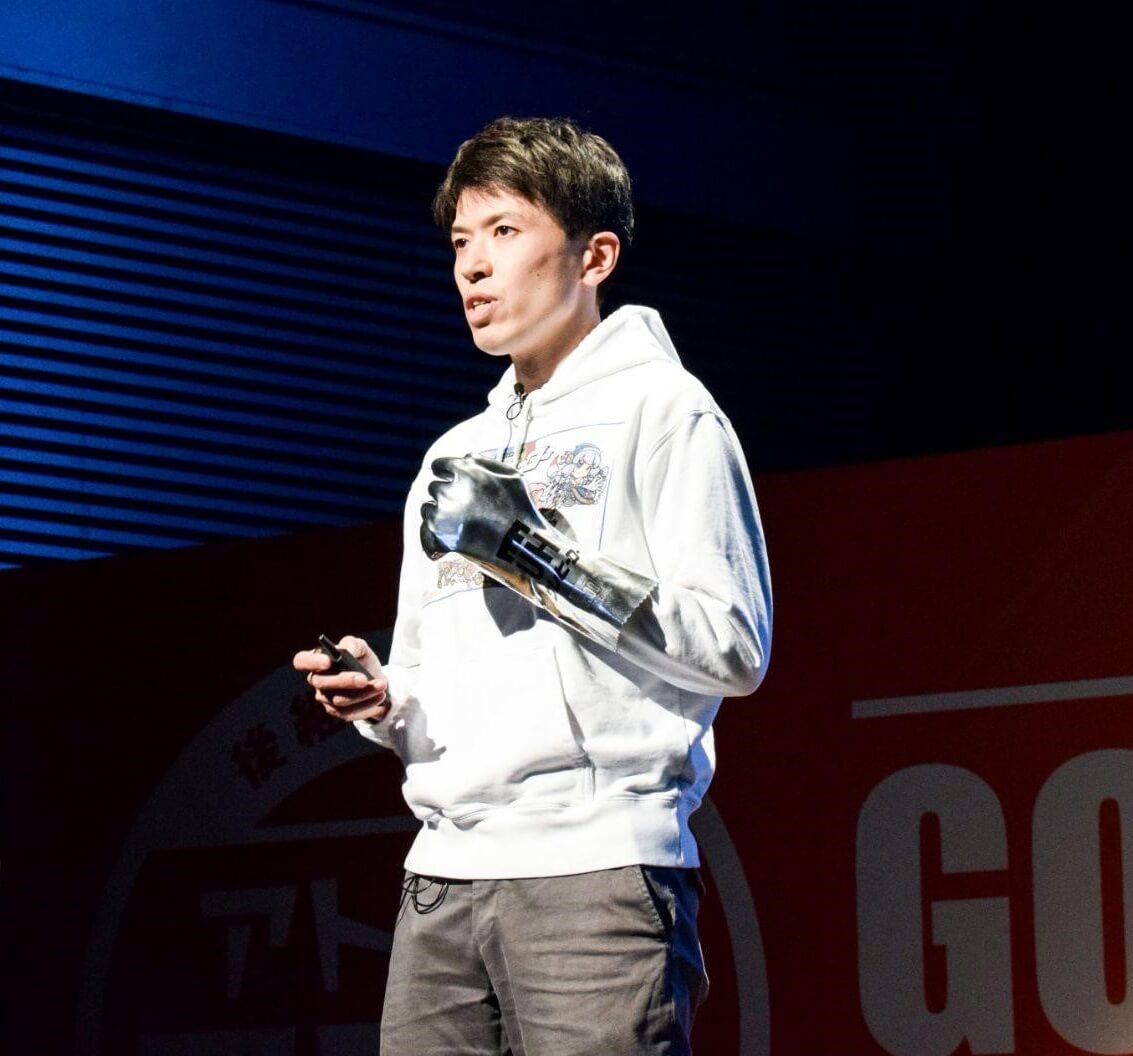 「斎藤塗料」の菅彰浩さんは、自社製品を利用したコスプレグッズを着けてスピーチ